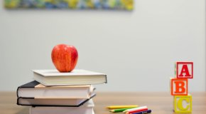 teacher's desk with apple notebooks and abc blocks